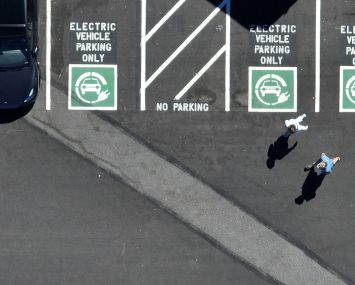 An aerial view of an electric vehicle charging station with pedestrians walking.